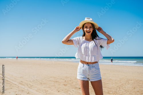 girl laughs, playfully pulling a hat on his head on the background of the ocean and sand
