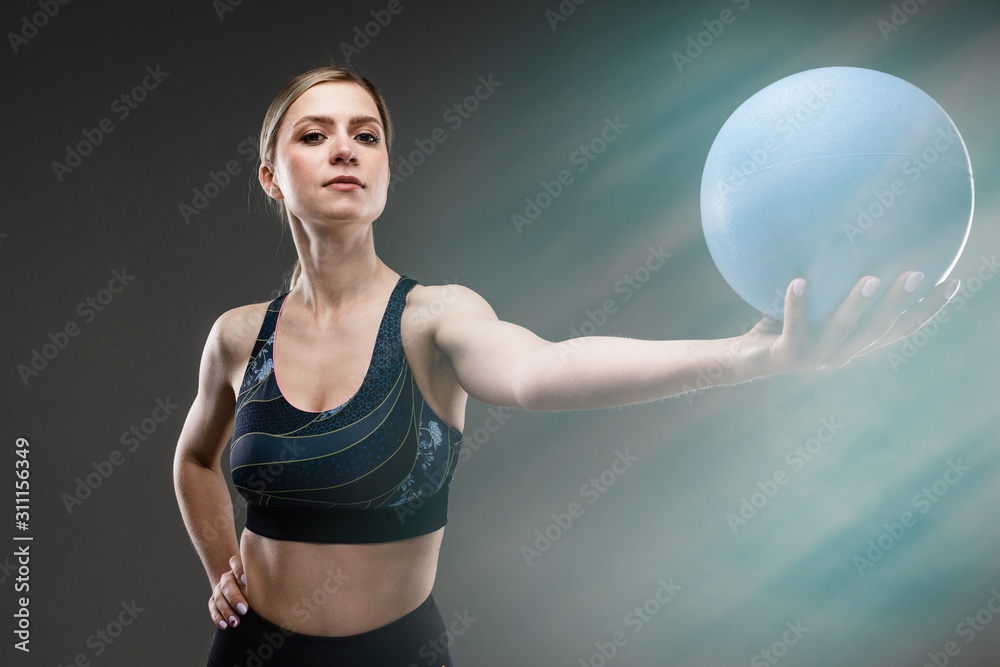 slim girl in sportswear holds a sports ball on a black background with lens flare effect slim girl in sportswear holds a sports ball on a black background with lens flare effect
