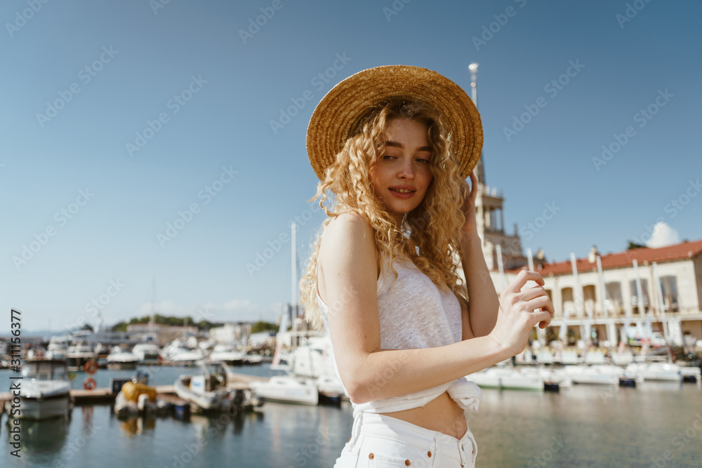 curly blonde in a hat on the background of the seaport and boats