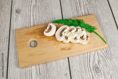 Mushroom champignon with rocket on the wooden cutting board. Vertical view photo