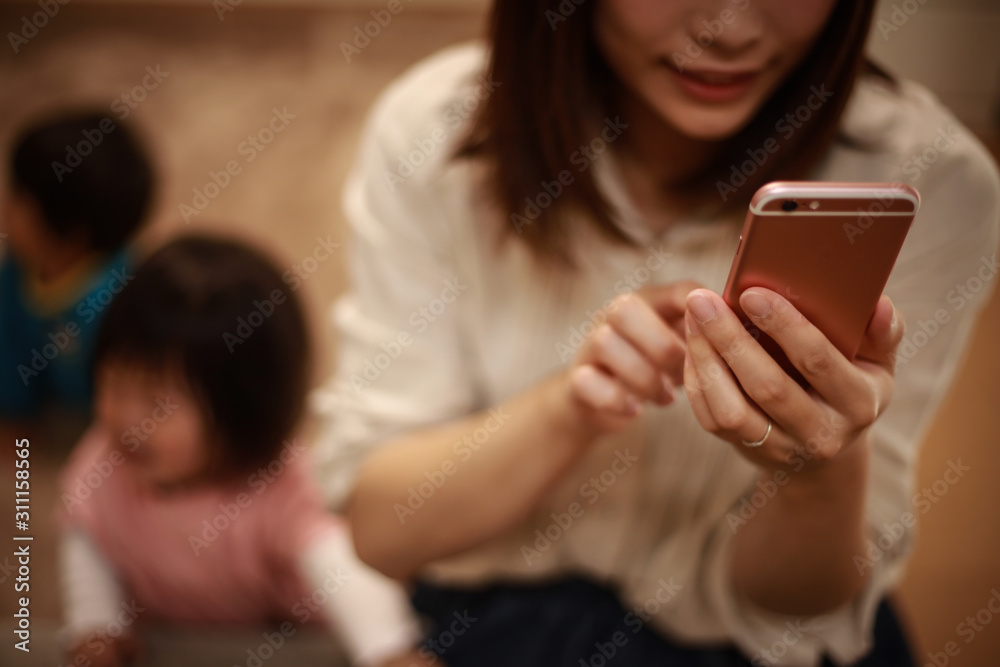 スマートフォンの操作に夢中になる母親 スマートフォンの操作に夢中になる母親
