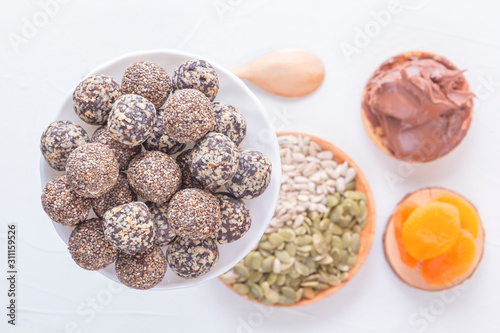Natural healthy raw energy bites, chocolate paste and mix of dried fruits with nuts on a white table. Top view