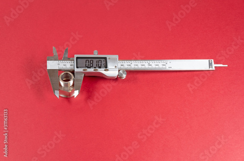 One metal vernier caliper on red background
