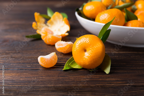 Tangerines mandarin with leaves in a plate on wooden background. Symbol Christmas food, copy space.