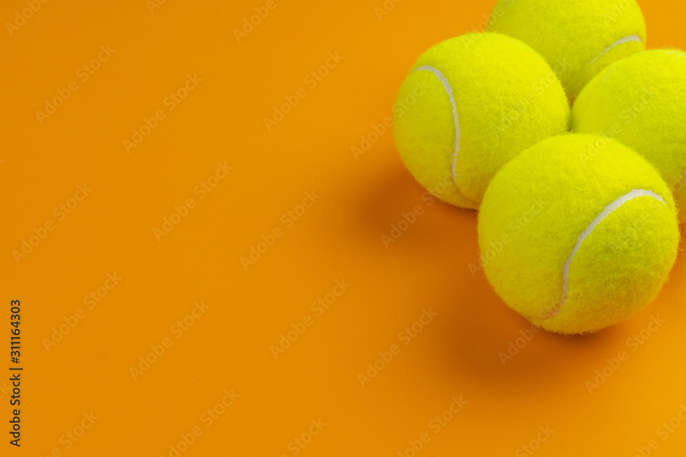 Four tennis balls on an orange background