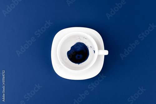 Top view of a cup of coffee on saucer on classic blue background