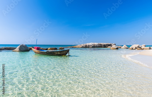 Boat in blue sea and white sand beach.