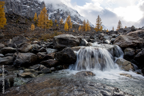 Small waterfall from stream high in mountains. Against background of snowy peaks. Beautiful photo