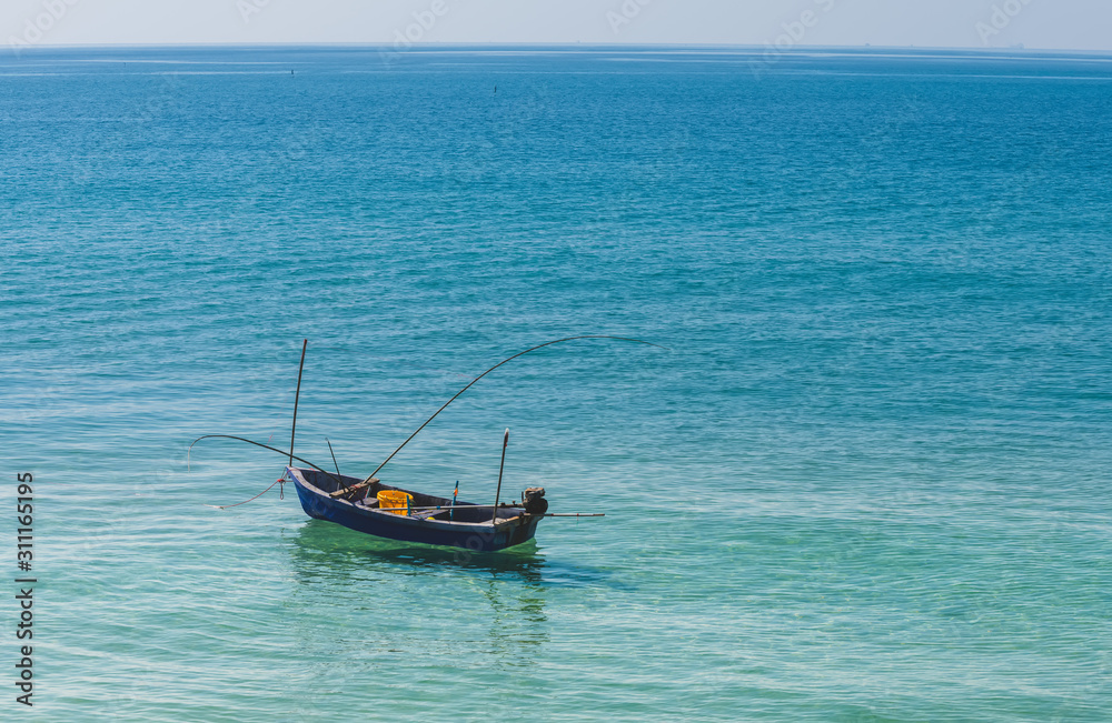 Small wooden fishing boat in the blue sea.