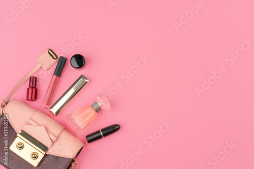 Fototapeta Naklejka Na Ścianę i Meble -  Female small handbag full of cosmetic products on bright pink background