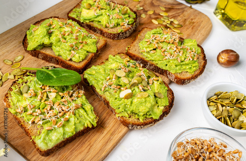 Sandwiches with avocado guacamole on a wooden board on the table. Healthy food concept.