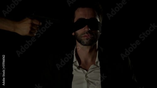  Kidnapper holds pistol directed at man head.