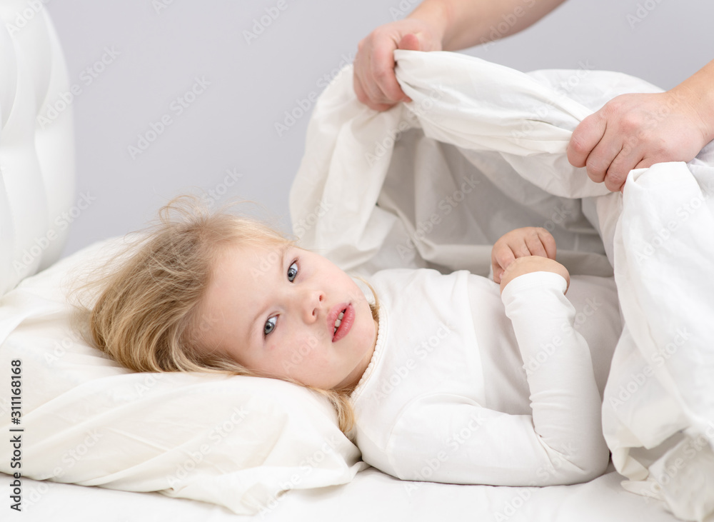 little girl mom hides the blanket on the bed