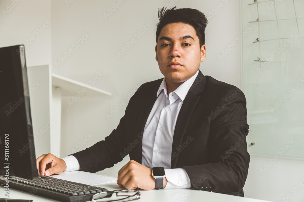 Young office worker sitting at desk, using computer. Two business man talking Young office worker sitting at desk, using computer. Two business man talking