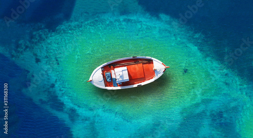 Aerial drone top down photo of traditional wooden fishing boat docked in Zakynthos island, Ionian, Greece