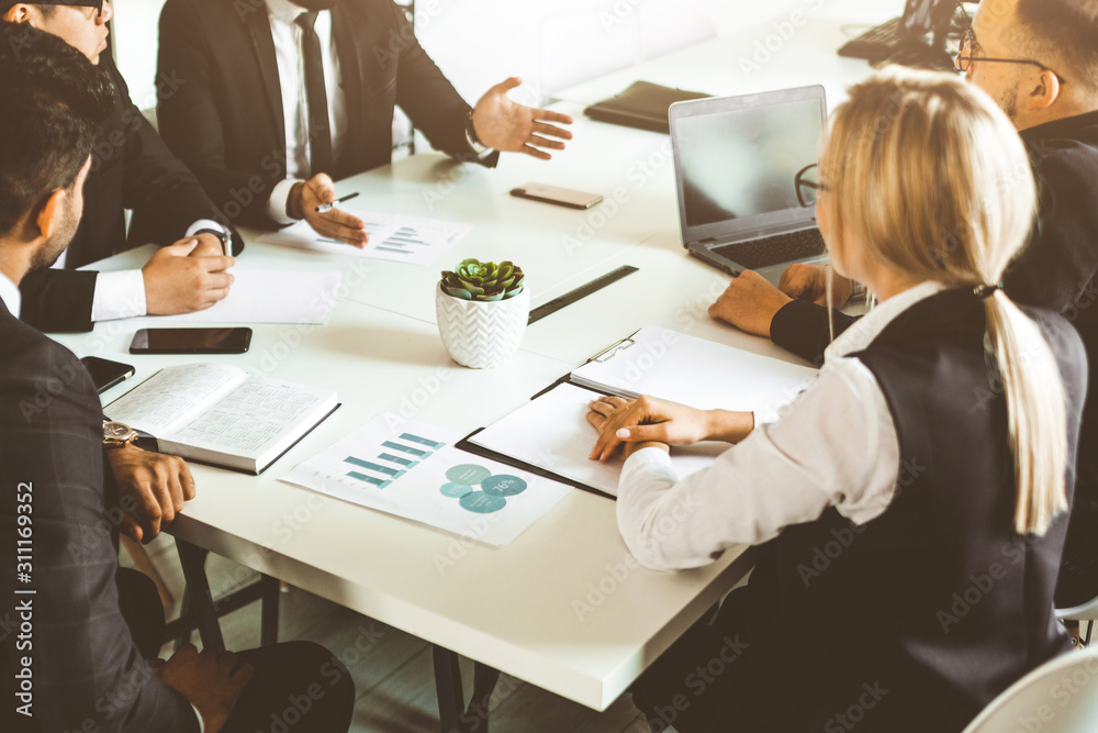 © xartproduction - A team of young businessmen working and communicating together in an office. Corporate businessteam and manager in a meeting.