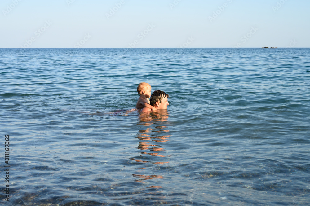 three year old little boy having fun at summer vacation in sea with his family
