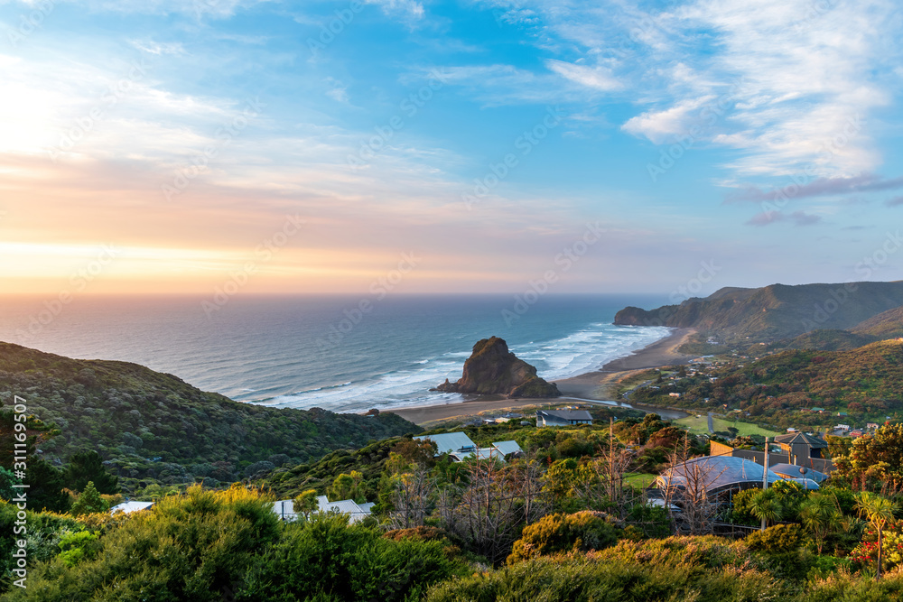 Wide-angle view of Piha beach with Lion Rock in sunset light