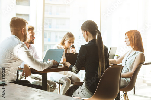 A team of young businessmen working and communicating together in an office. Corporate businessteam and manager in a meeting.