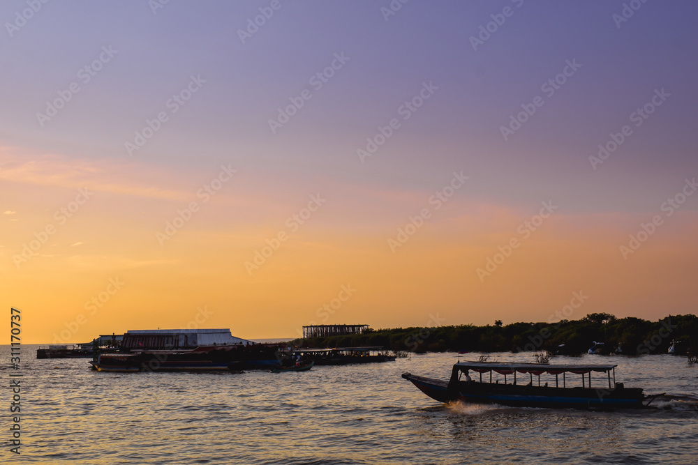 Tourist boat driving high speed on the Tonle Slap Lake in Cambodia during beautiful Sunrise