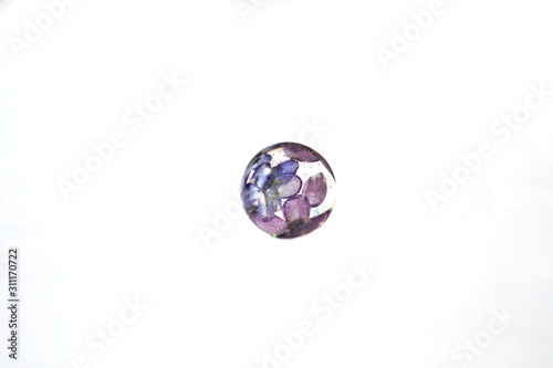 Beautiful violet lilac flower in epoxy resin ball. Handmade decoration isolated on white background, suitable for text input. Situated top left. 