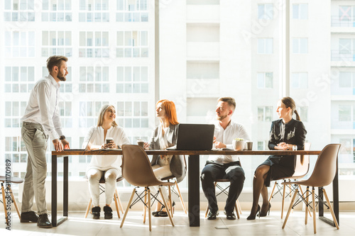 A team of young businessmen working and communicating together in an office. Corporate businessteam and manager in a meeting. desktop against the background of the pan window, free space for text
