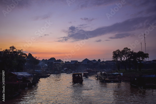 Tourist boats driving through floating native floating village on pylons Kampong Phluk in Cambodia Asia © MartinZizlavsky