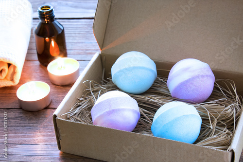 Colorful bath bombs in a gift box, candles and aroma oil on a dark wooden background. Aromatherapy and spa concept.