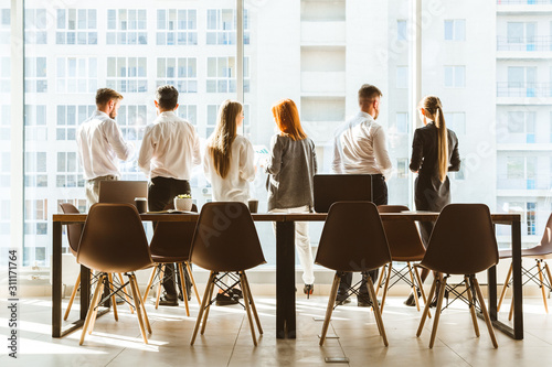 A team of young businessmen working and communicating together in an office. Corporate businessteam and manager in a meeting. desktop against the background of the pan window, free space for text
