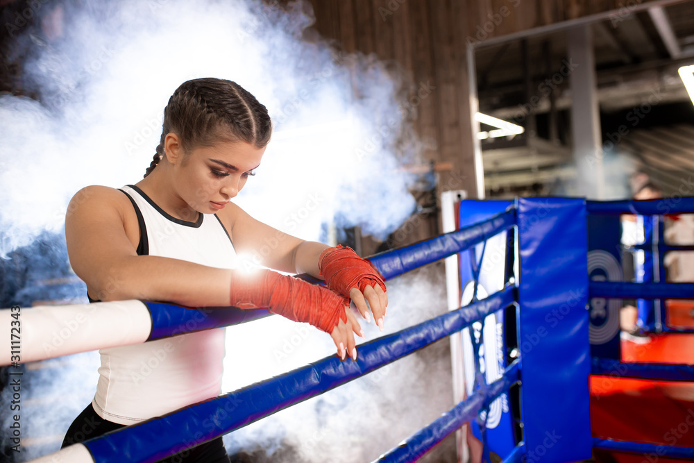 tired caucasian woman boxer stand leaning on the fence, after successful training in the ring. Sport concept