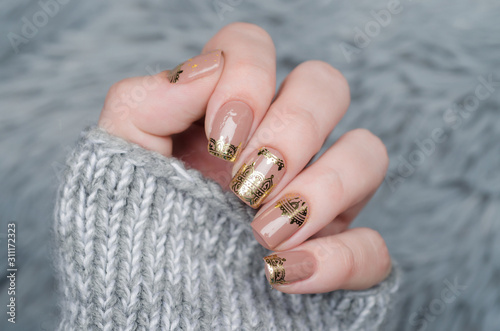 beige Nude manicure with gold lace pattern on a gray background