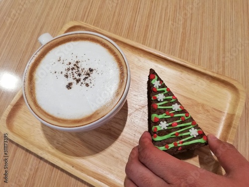 Hot cappuccino and brownie shaped Christmas tree on wooden background photo