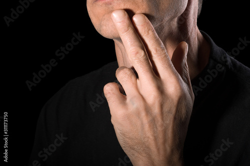 The man shaved his beard and touched his face. Close-up, black background.