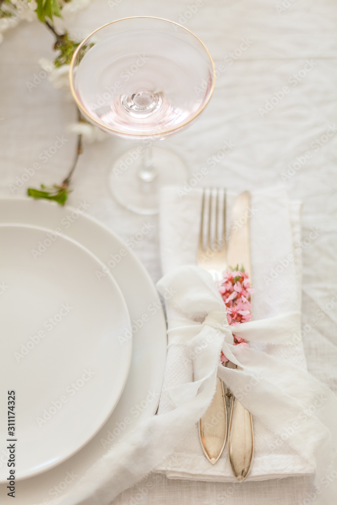 Elegant white table setting with silver cutlery, white plates and linen tablecloth. Wedding dinner decorations in white colour Elegant white table setting with silver cutlery, white plates and linen tablecloth. Wedding dinner decorations in white colour