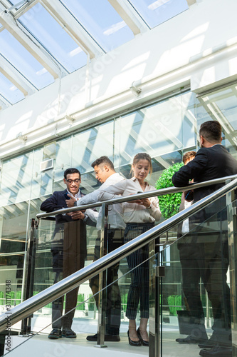 young business people are standing and talking on the background of glass offices. Corporate businessteam and manager in a meeting.