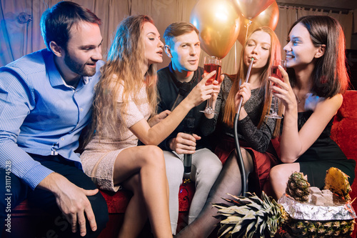 group of trendy young singers have fun together in karaoke bar, fashionable and positive guys and ladies celebrating, singing. positive pastime
