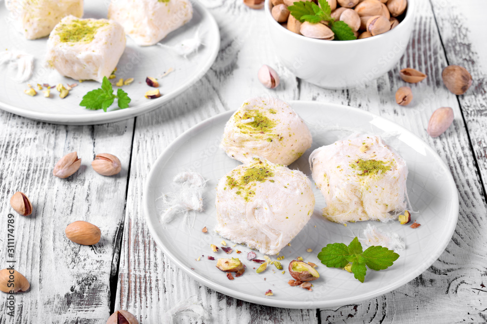 Cotton candy with pistachio on ceramic plate on white wooden table Cotton candy with pistachio on ceramic plate on white wooden table
