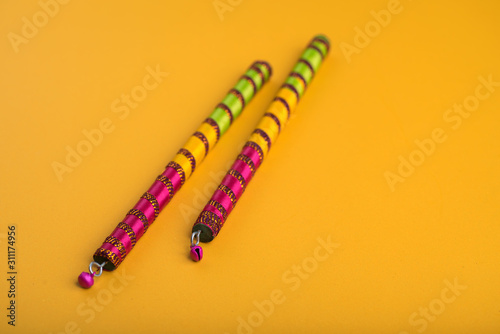 Dandiya sticks on a yellow background. Raas Garba or Dandiya Raas is the traditional folk dance form the state of Gujarat & Rajasthan in India. photo