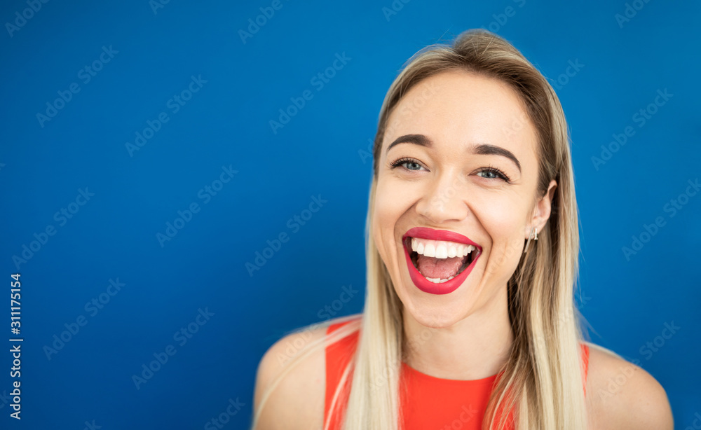Attractive wide smiling blonde woman. Beautiful red lips and blue background