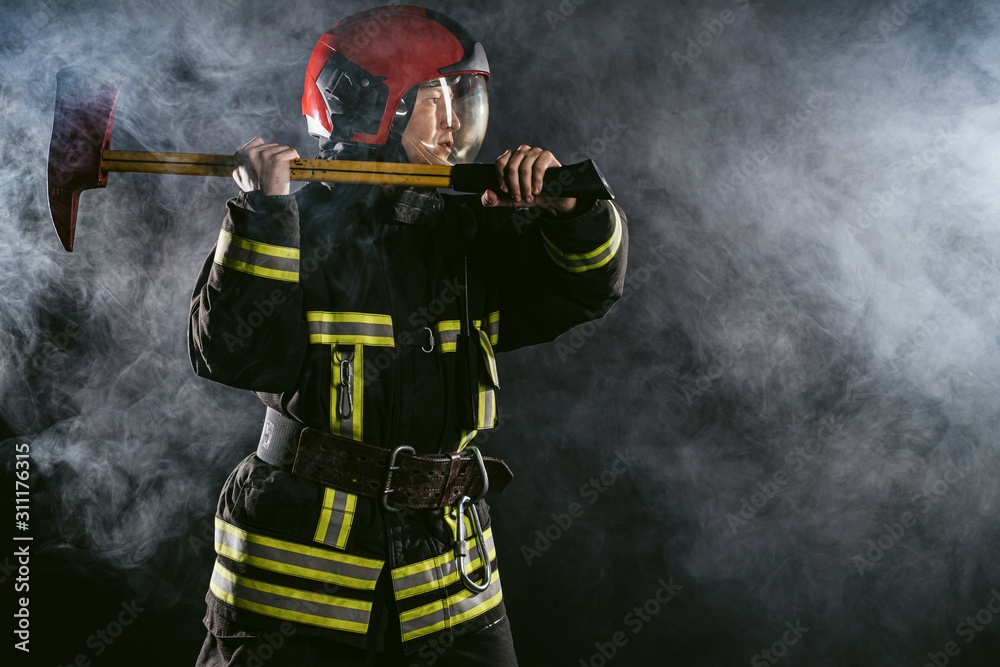 Fototapeta premium reverent, confident man working in fire station ready to save people from fire in emergency situations, wearing uniform and helmet