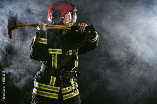 reverent  confident man working in fire station ready to save people from fire in emergency situations  wearing uniform and helmet