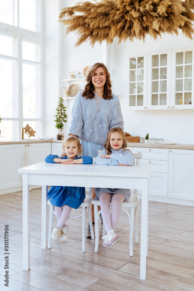 Mom with her two children sitting on the kitchen table and eating candies. Mother with daughter and toddler son having breakfast at home. Happy lifestyle family moments. Mom with her two children sitting on the kitchen table and eating candies. Mother with daughter and toddler son having breakfast at home. Happy lifestyle family moments.