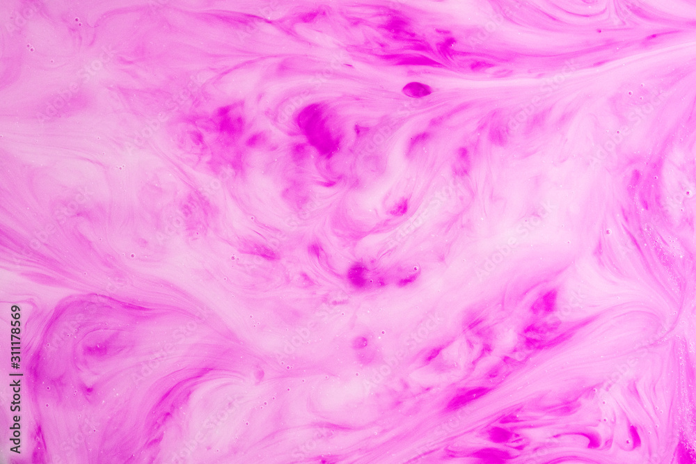 A macro photo of drops of pink food dye swirled and mixed into thick creamy white milk to give a marbled milkshake effect
