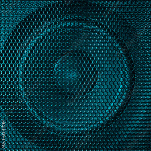 A close up macro photo of a speaker lit with a vibrant turquoise aqua teal flash gel
