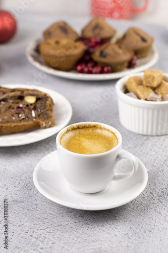 a cup of coffee, a slice of chocolate cake and muffins on the table