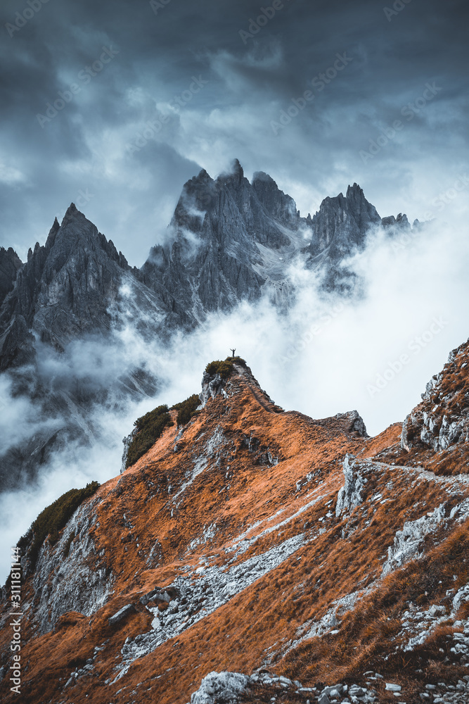 Φωτογραφία Man standing on edge of mountain feeling victorious with arms up in the air