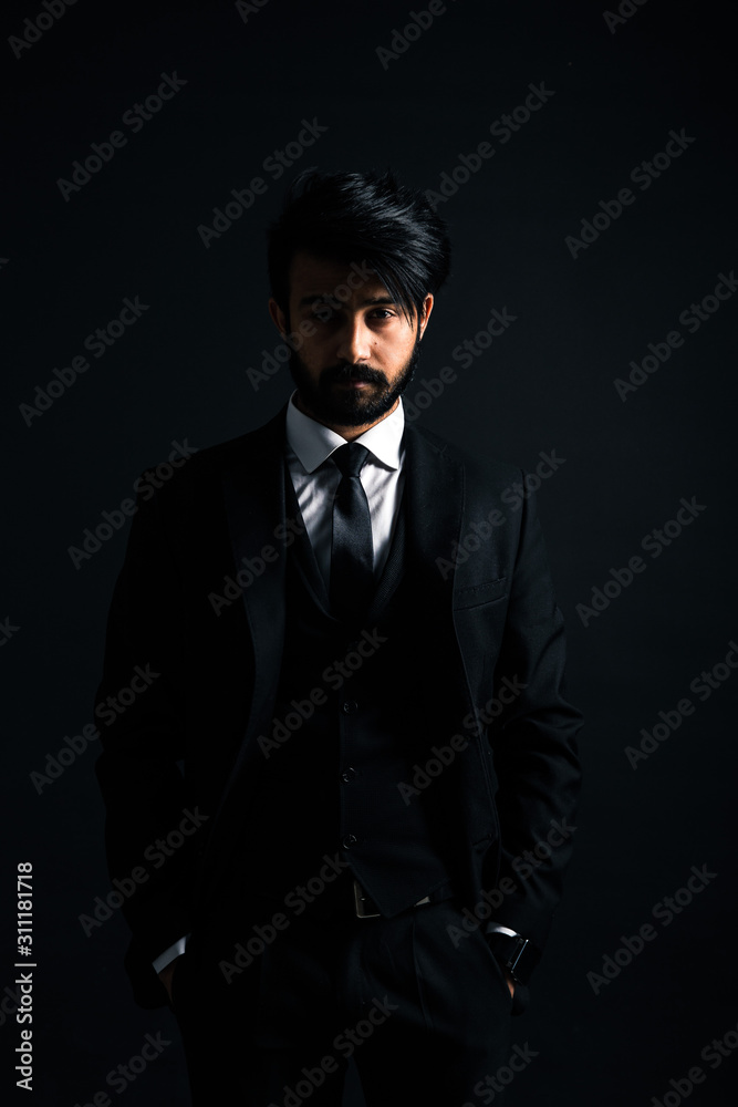 Portrait of a young handsome successful Indian in a classic black three-piece business suit on a dark background Portrait of a young handsome successful Indian in a classic black three-piece business suit on a dark background