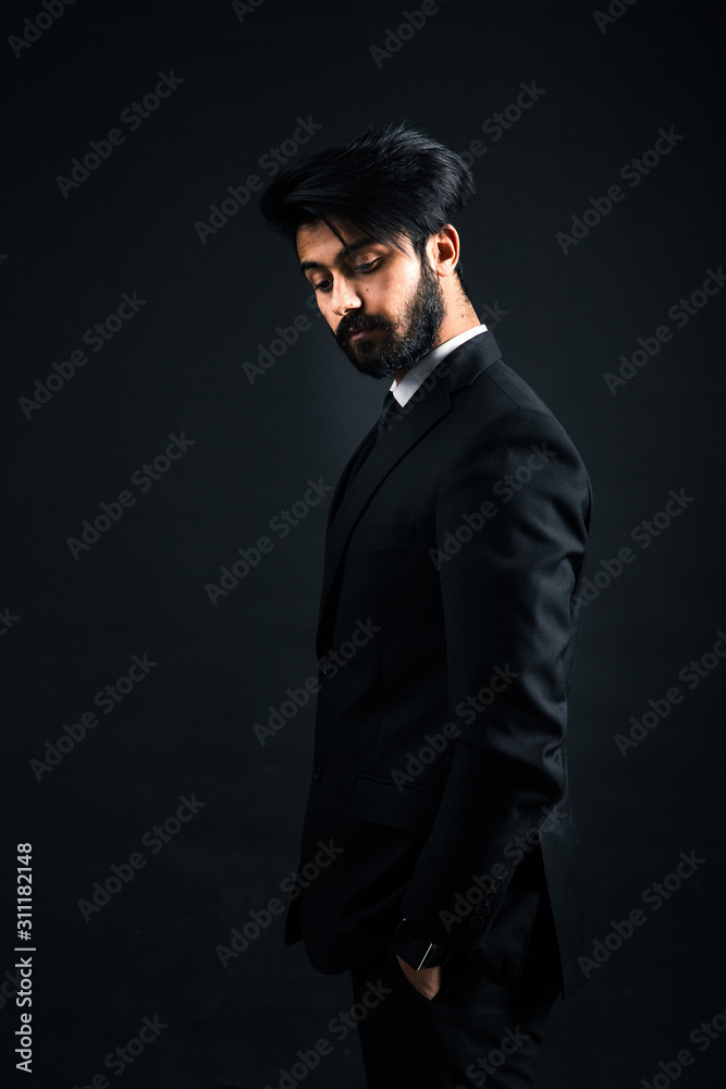 Portrait of a young handsome successful Indian in a classic black three-piece business suit on a dark background Portrait of a young handsome successful Indian in a classic black three-piece business suit on a dark background