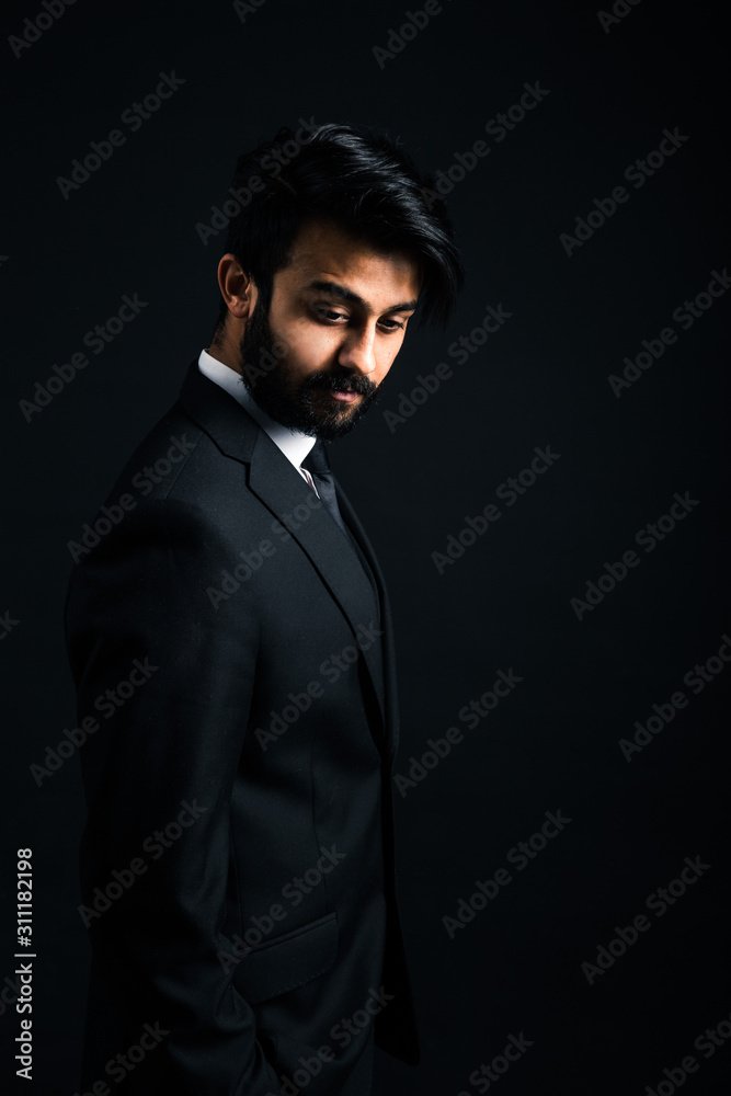 Portrait of a young handsome successful Indian in a classic black three-piece business suit on a dark background Portrait of a young handsome successful Indian in a classic black three-piece business suit on a dark background