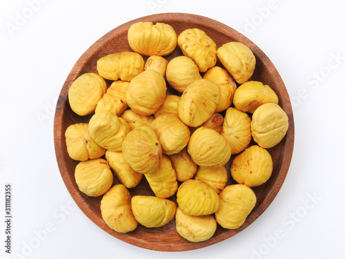 Top view of a pile of yellow peeled chestnuts on wooden plate isolated on white background. Food concept. Ingredient used for cook.